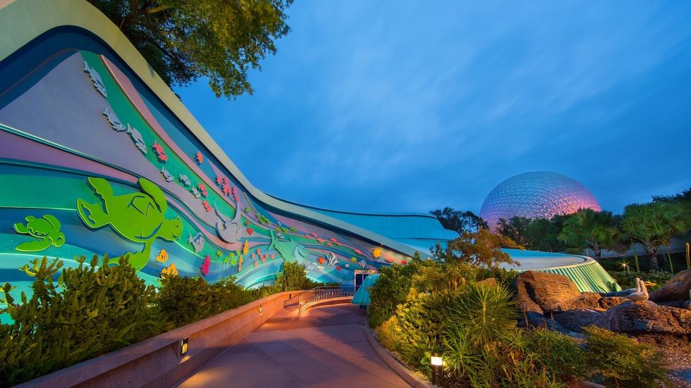 Colorful ocean-themed building at twilight with a geodesic dome in the background at Epcot