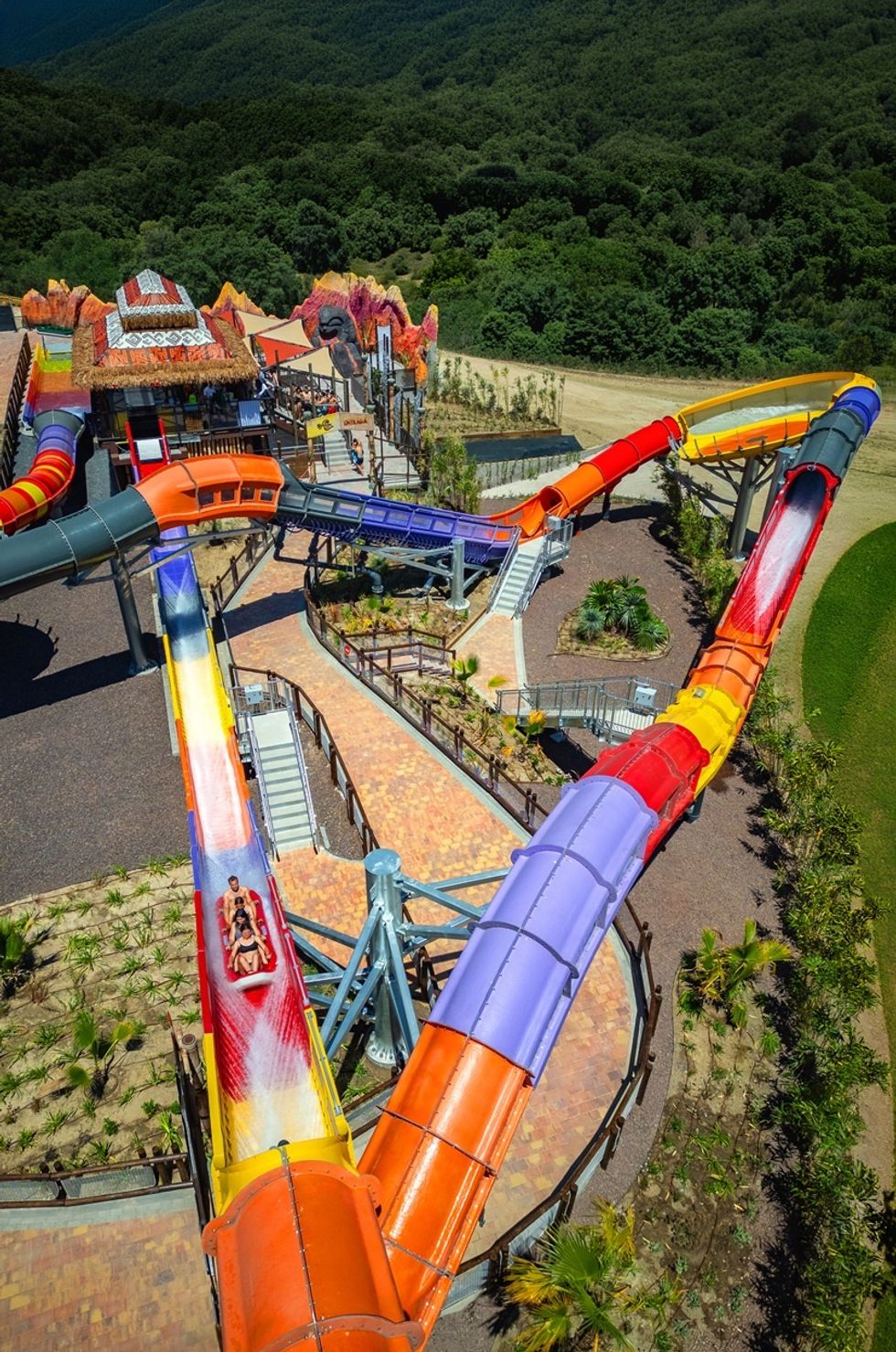 Colorful outdoor water slide at a park surrounded by lush greenery.