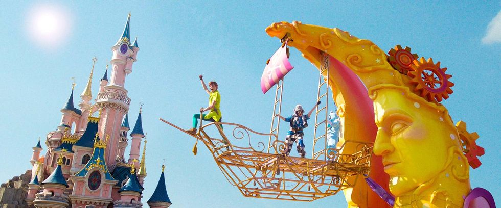 Colorful parade float near a fairytale castle under a sunny blue sky.
