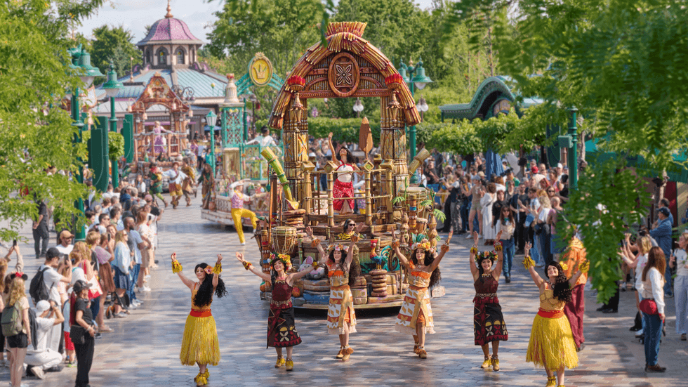 Colorful parade with dancers and a tropical-themed float at Disneyland Paris