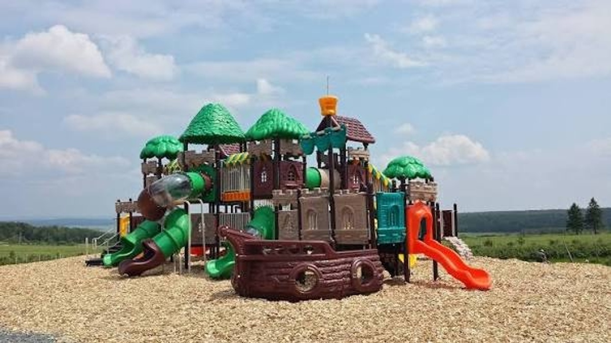 Colorful pirate ship playground set with slides and towers on a sunny day.