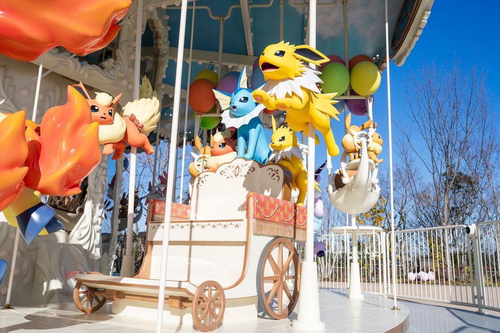 Colorful Pok\u00e9mon-themed carousel with lively figures, set against a clear blue sky.