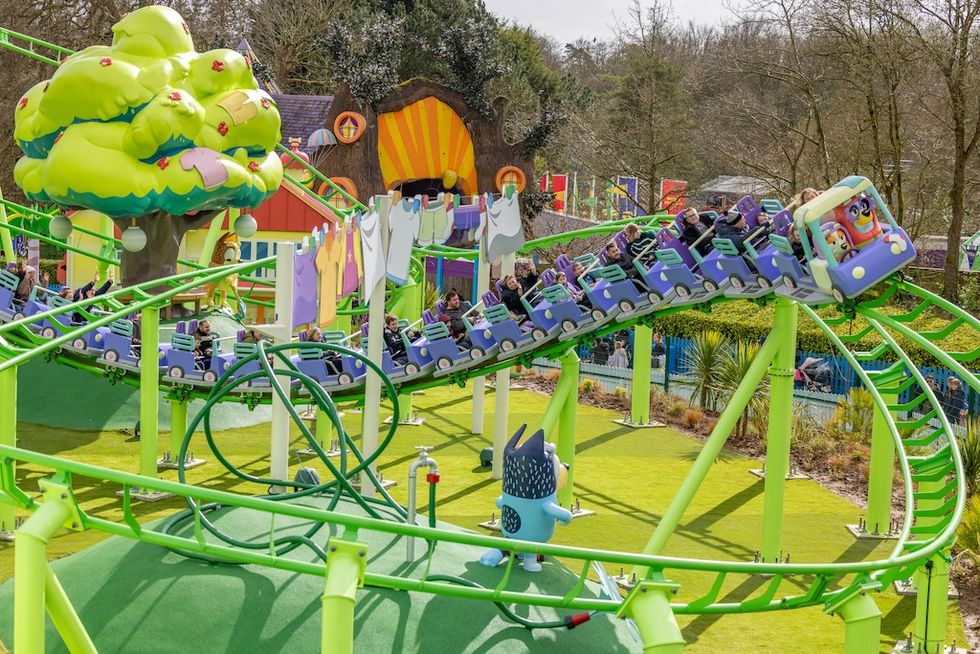 Colorful roller coaster with cartoon theme, green track, and riders enjoying the ride.