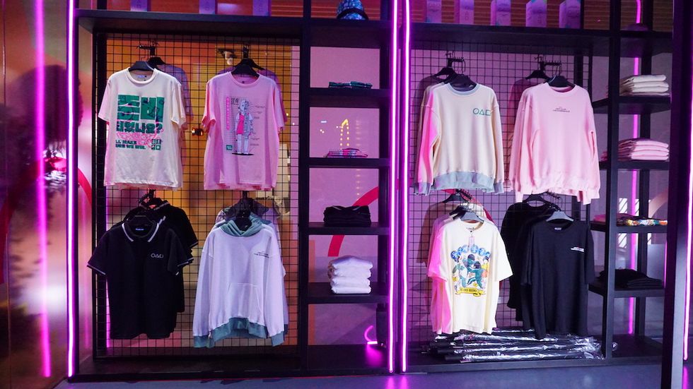 Colorful shirts displayed on racks with neon pink lighting.