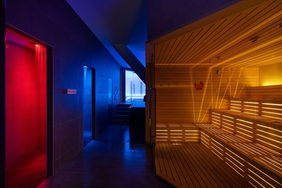 Colorful spa interior with sauna, blue hallway, and red-lit shower.