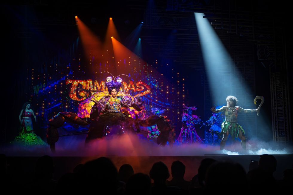 Colorful stage performance with elaborate costumes under dramatic lighting.