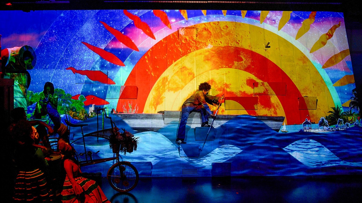 Colorful stage projection with sun, ocean waves, and red fish swimming.