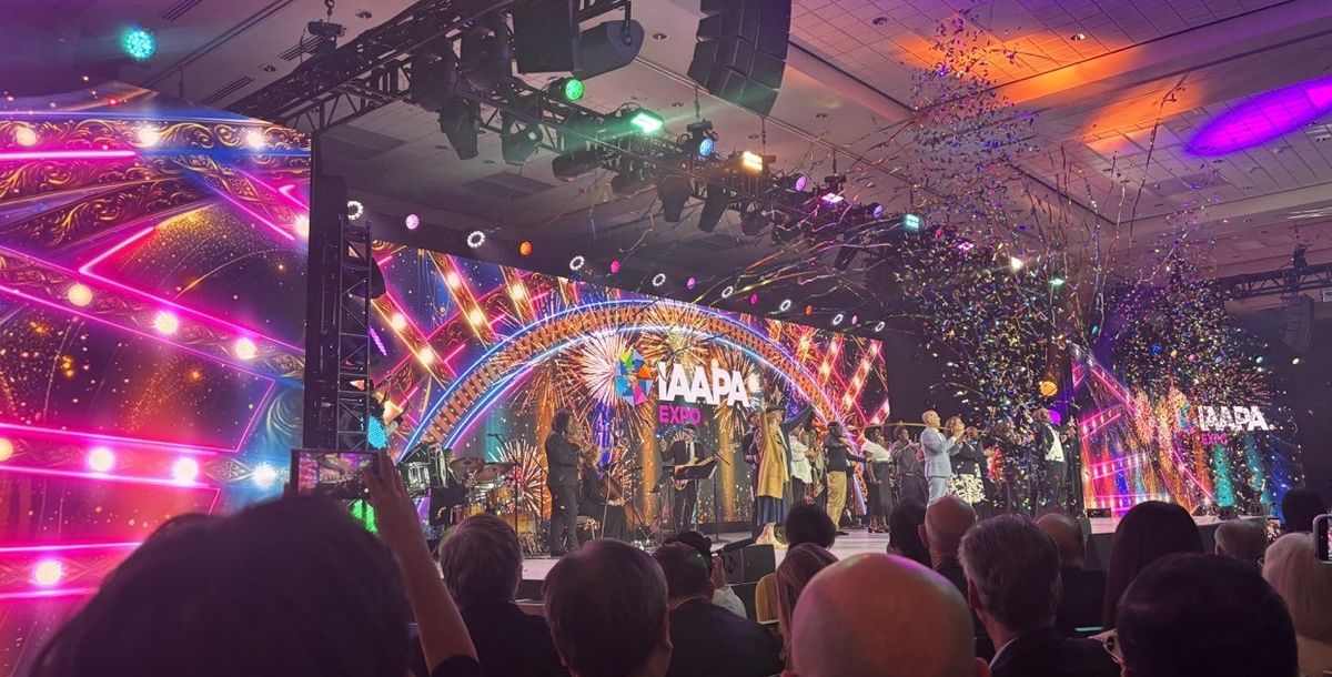 Colorful stage with confetti at IAAPA Expo event, featuring vibrant lights and fireworks.