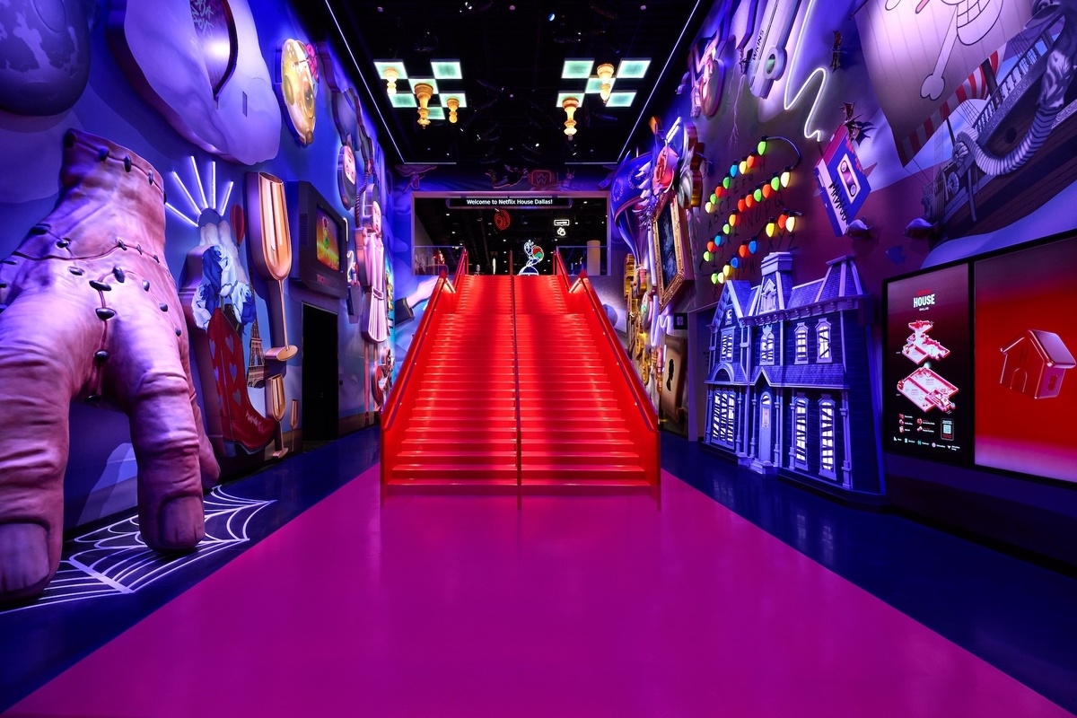 Colorful, surreal hallway with vibrant red stairs and eclectic wall art.