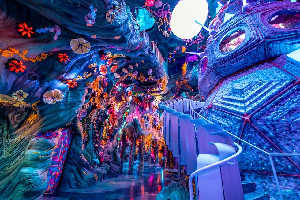 Colorful, surreal indoor space called Meow Wolf with vibrant, glowing alien-like flora and structures.