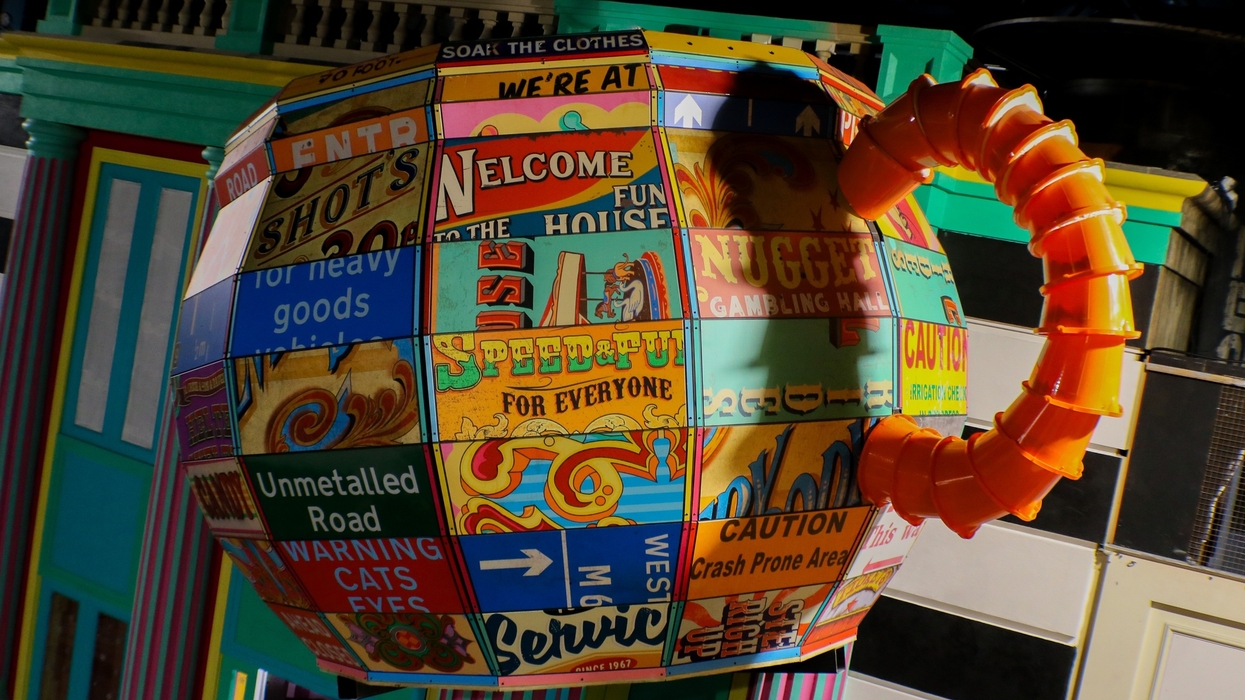 Colorful teapot sculpture with patchwork sign designs and an orange handle at Absurd City