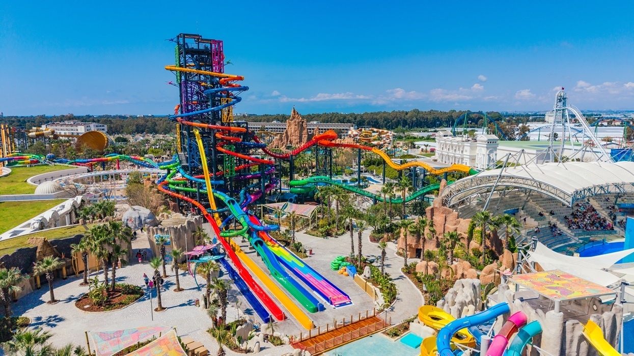 Colorful, towering water slides at an amusement park under a clear blue sky.