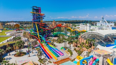 Colorful, towering water slides at an amusement park under a clear blue sky.