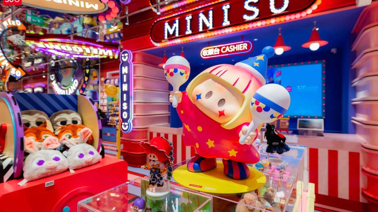 Colorful toy display at a bright Miniso store with plush animals and cashier in the background.