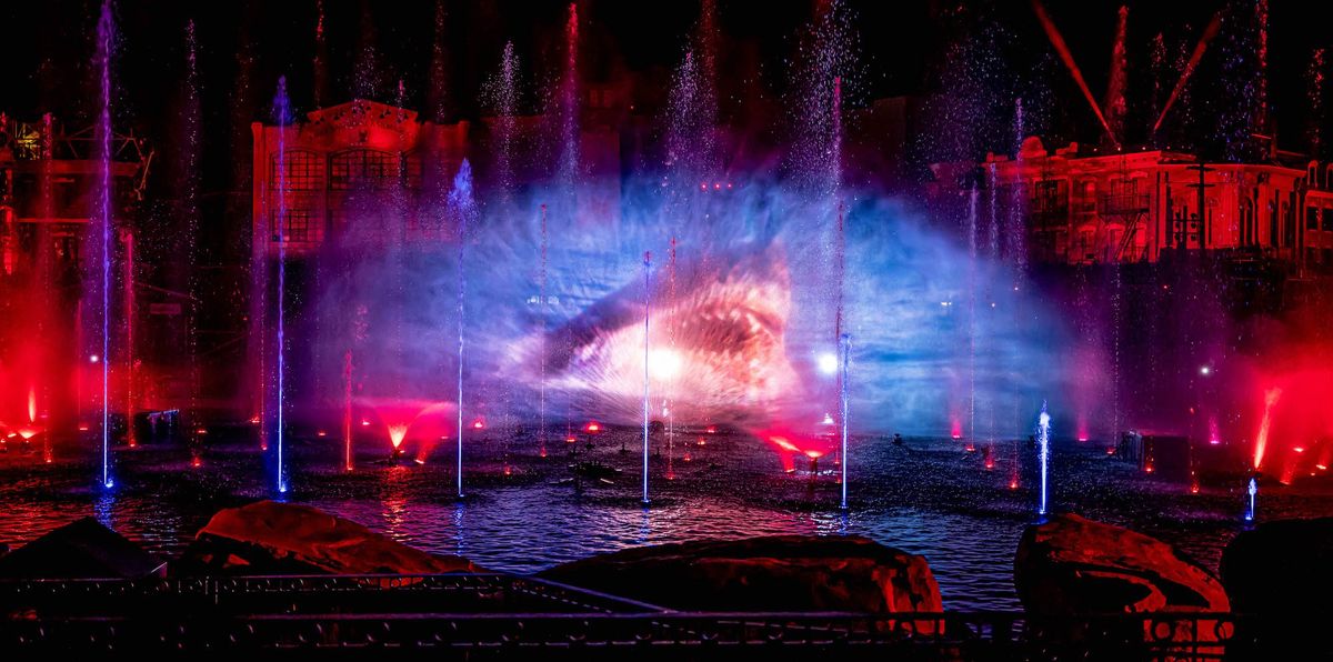 Colorful water fountain light show at night with vivid red, blue, and purple illumination.