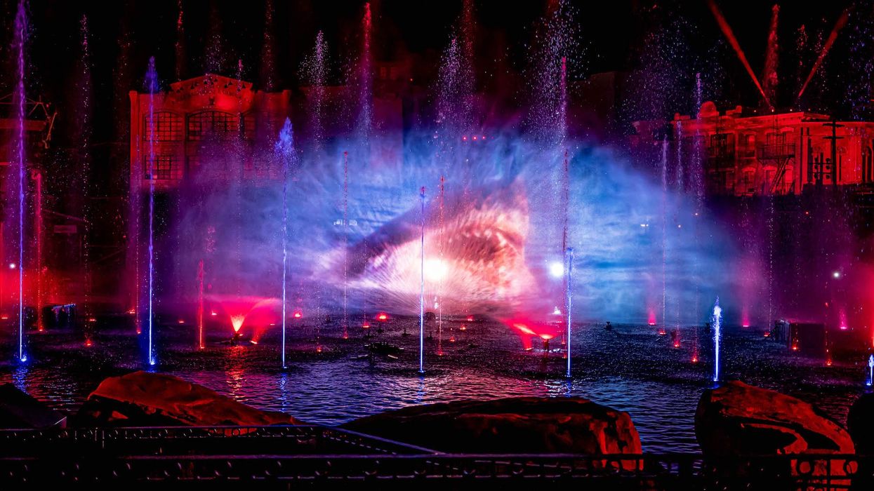 Colorful water fountain light show at night with vivid red, blue, and purple illumination.