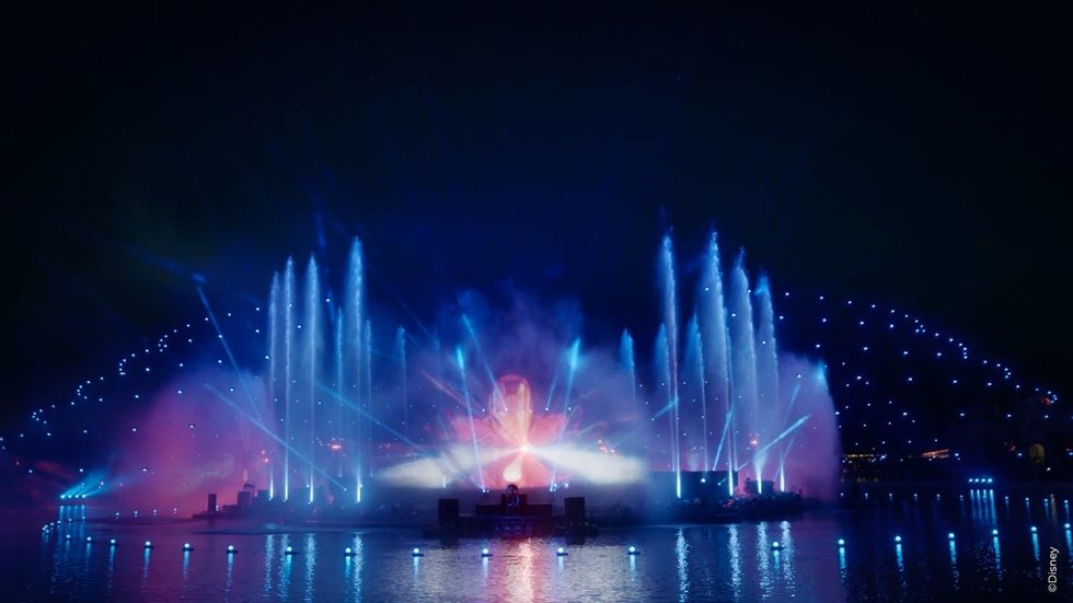 Colorful water fountain show with lights reflecting on a lake at night.