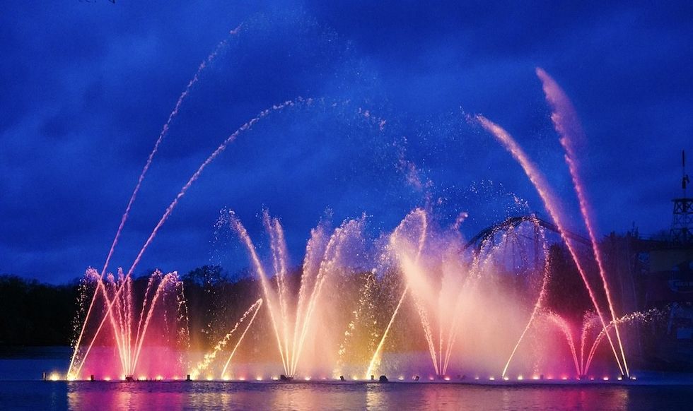 Colorful water fountains illuminated at night against a deep blue sky.