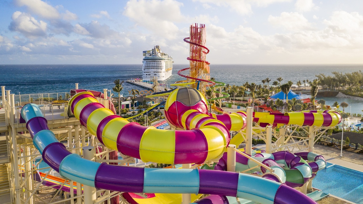 Colorful water park slides with ocean and cruise ship in the background.