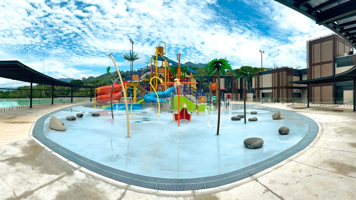 Colorful water park with slides and fountains under a blue sky.