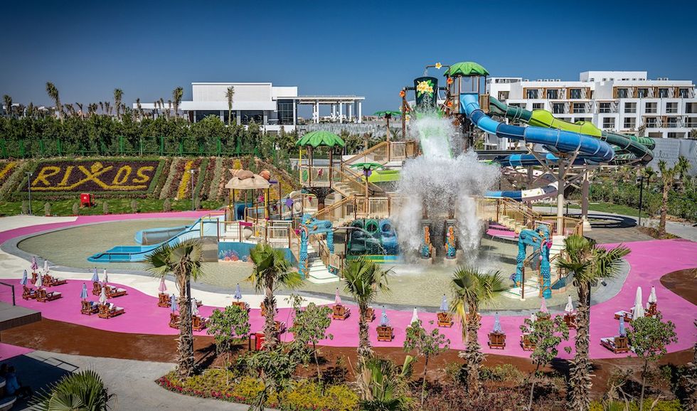 Colorful water park with slides and splash features under a clear blue sky.