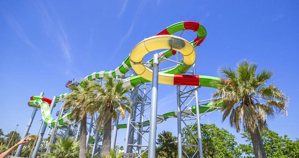 Colorful water slide towering over palm trees under a clear blue sky at Schlitterbahn Galveston