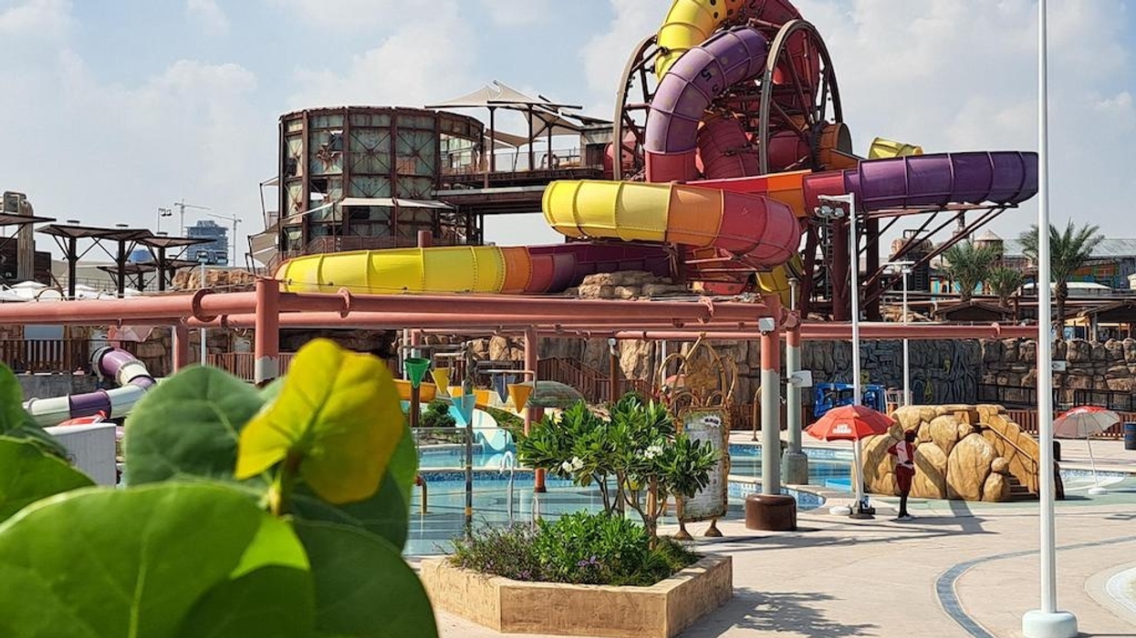 Colorful water slides at a water park under a cloudy sky.