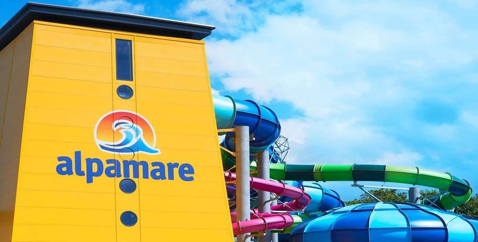 Colorful water slides beside a yellow building with an Alpamare sign.