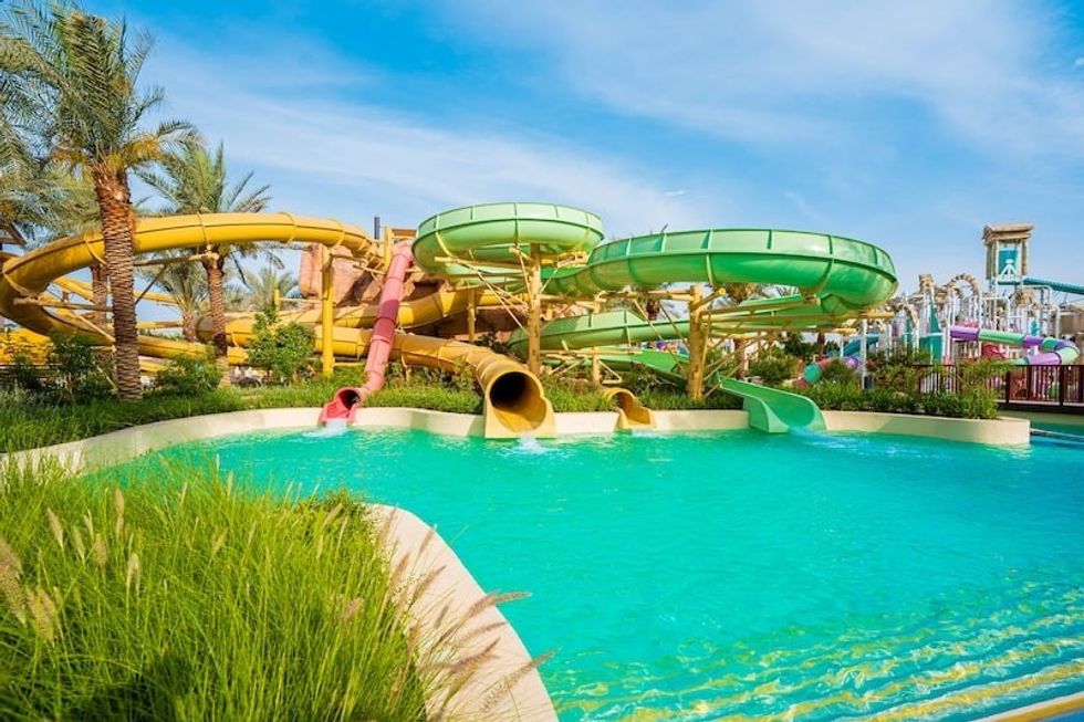 Colorful water slides by a pool in a tropical-themed water park, Saraya Aqaba Waterpark