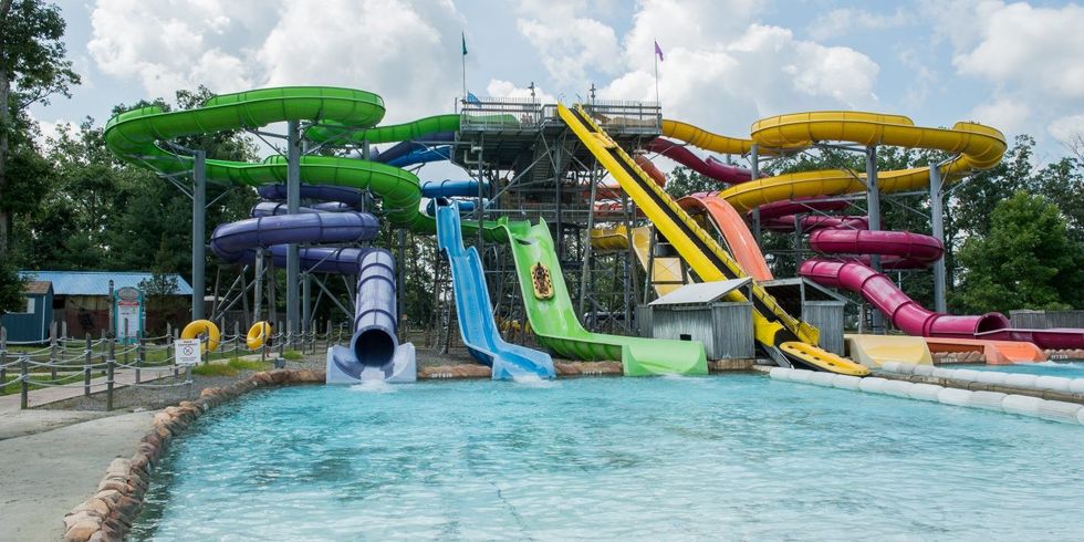 Colorful water slides leading to a pool at an outdoor water park called Six Flags Hurricane Harbor New Jersey