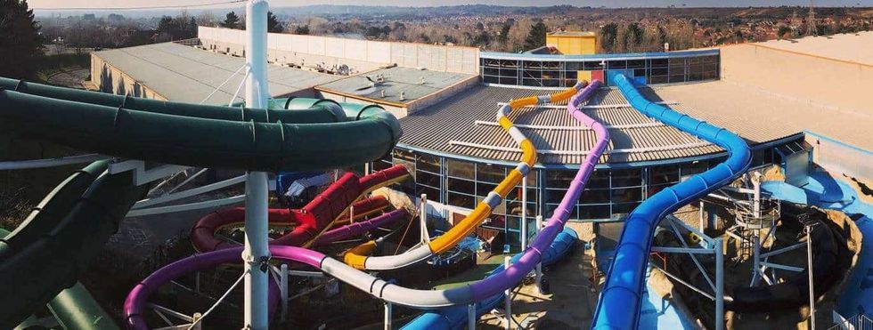 Colorful water slides weaving around a large building at an indoor water park, Splashdown Poole