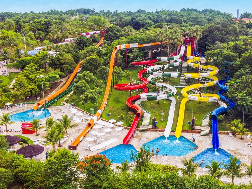 Colorful water slides winding through a lush, tropical water park called Thermas de S\u00e3o Pedro