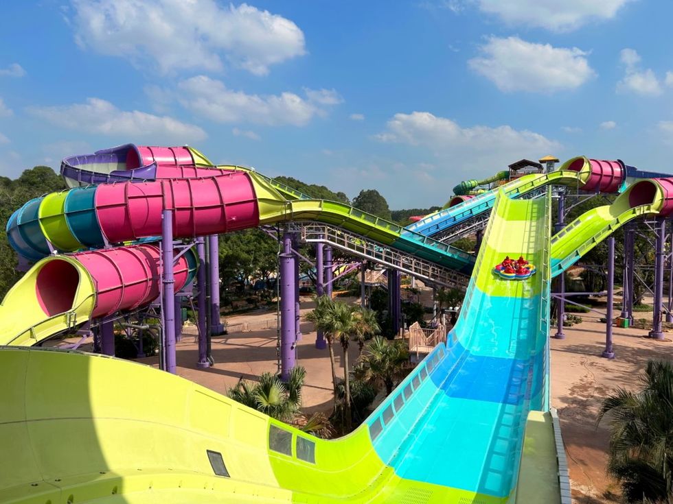 Colorful water slides with tubes and rafts at Chimelong water park under a blue sky.