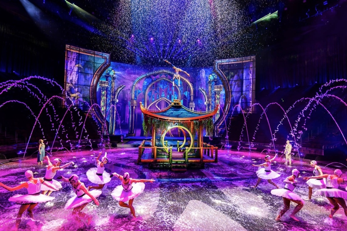 Colourful ballet performance named The House of Dancing Water, with water fountains and vibrant lighting on stage.