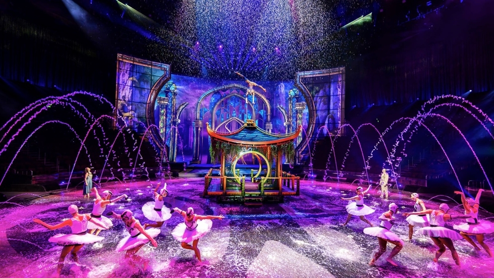 Colourful ballet performance named The House of Dancing Water, with water fountains and vibrant lighting on stage.