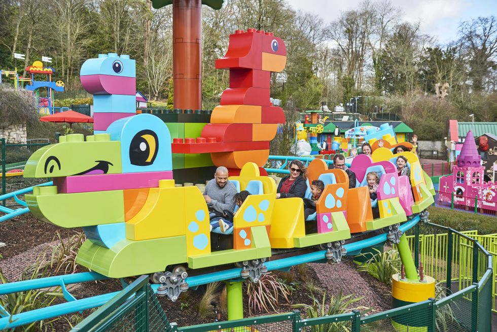 Colourful dragon-themed roller coaster at with smiling riders at Legoland Windsor in England.