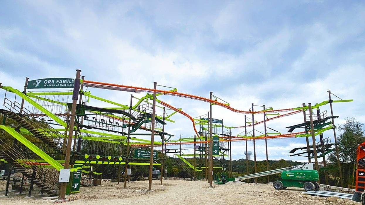 Colourful multi-level ropes course against a cloudy sky.