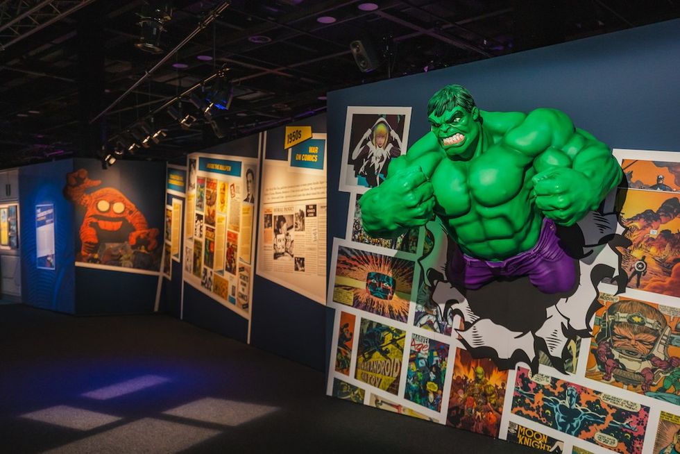 Comic exhibit with a Hulk bust and colorful illustrated panels on the walls.