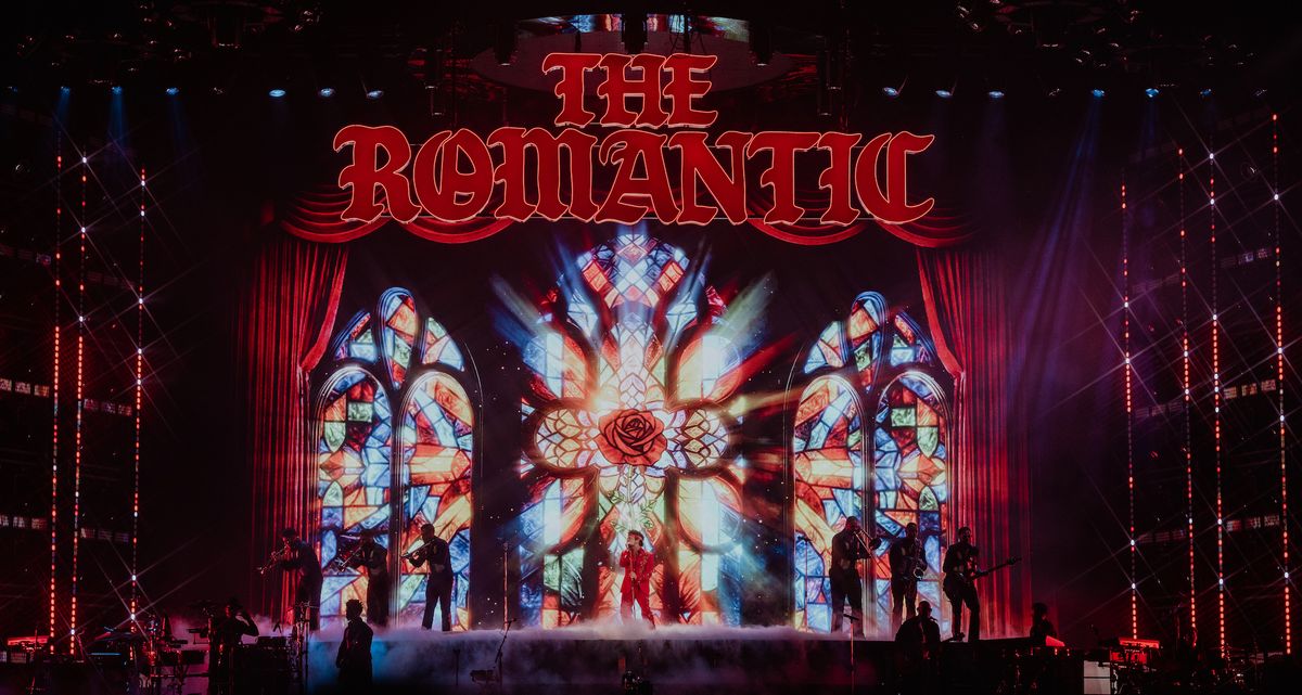 Concert stage with band, stained glass backdrop, and "The Romantic" in red letters.