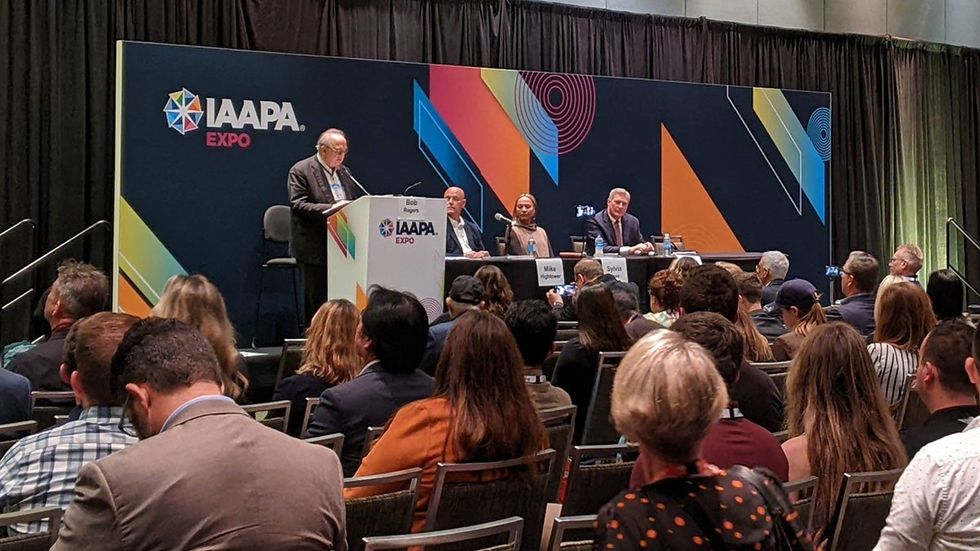 Conference panel at IAAPA Expo with a speaker and audience attentively listening.