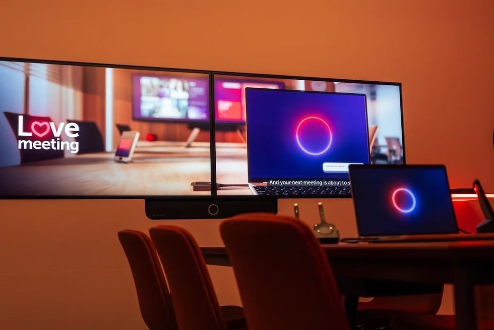 Conference room with screens displaying "Love meeting" and glowing circle graphics.