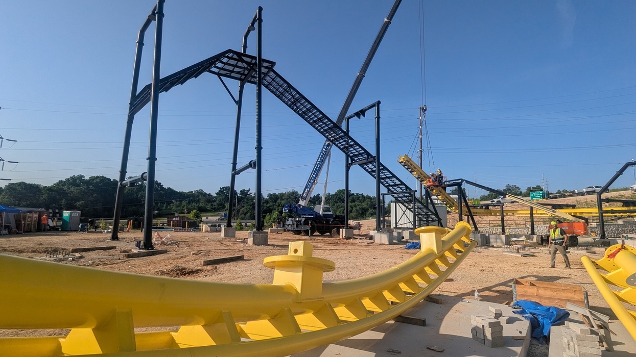 Construction of a yellow roller coaster with cranes and workers at Oasis at Lake of the Ozarks