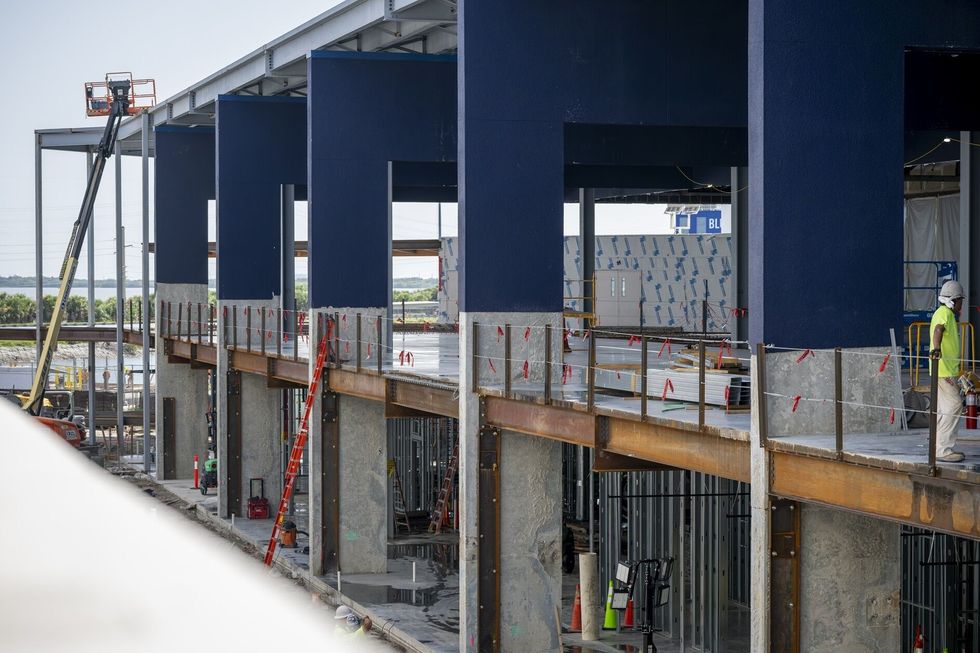 Construction site with steel beams and workers on a raised platform at Port Canaveral