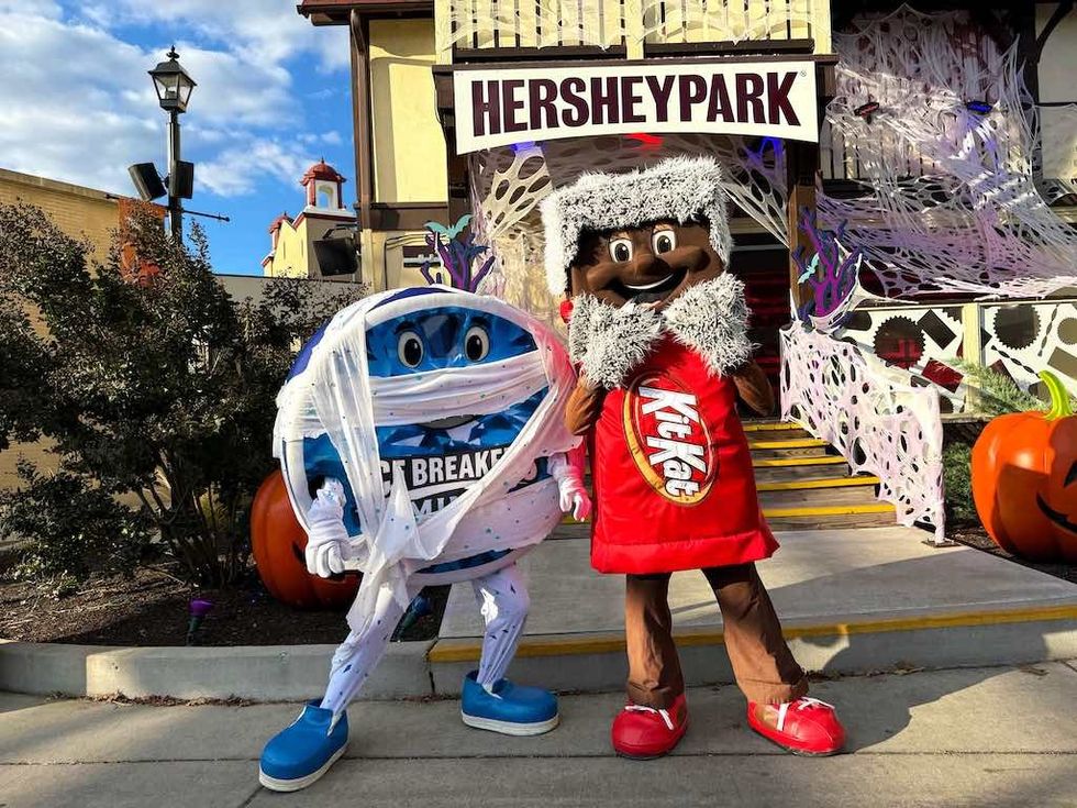 Costumed characters at Hersheypark entrance with festive Halloween decor.