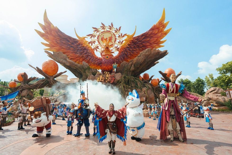 Costumed performers pose beneath a giant phoenix sculpture at Ziyang Fantawild Oriental Legend Park