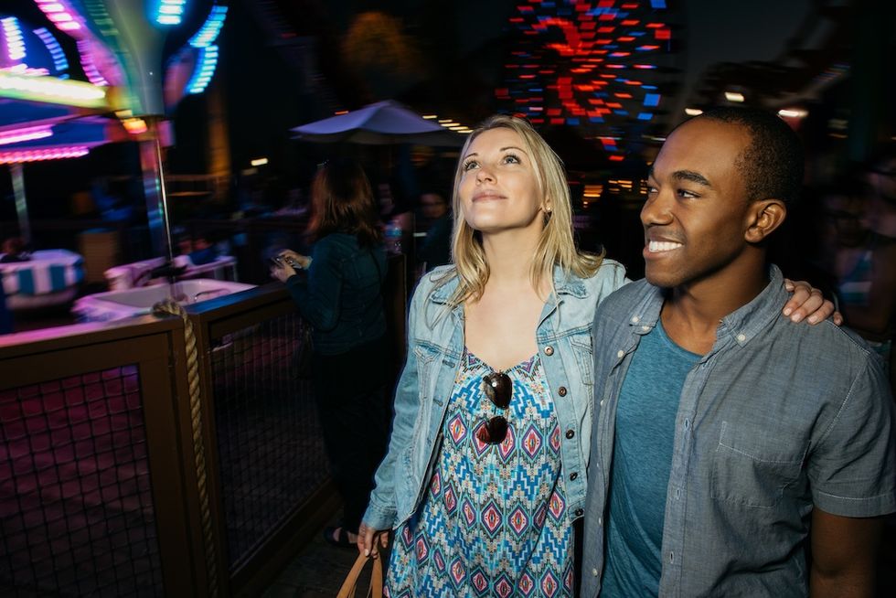 Couple enjoying a night at a colorful amusement park.