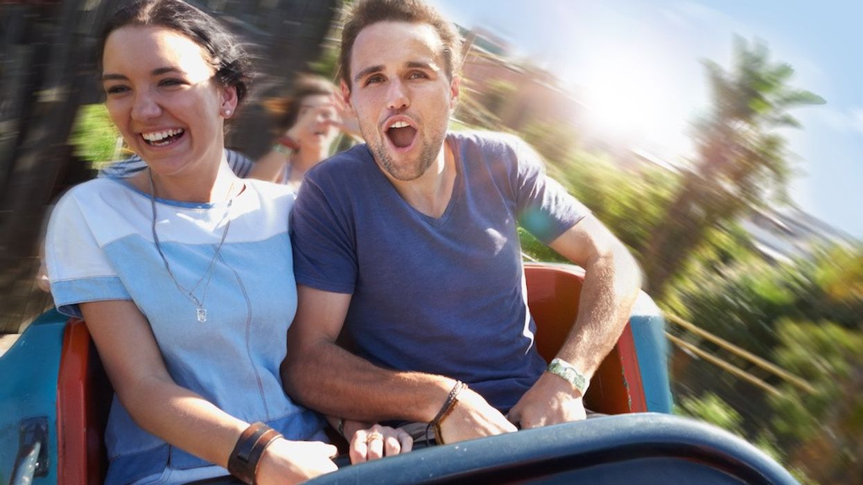 Couple enjoying a thrilling roller coaster ride on a sunny day.