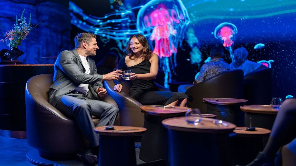 Couple enjoying drinks at Europa-Park's Eatrenalin with glowing jellyfish projections on the walls.