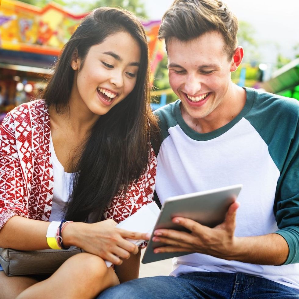 Couple look at mobile device at amusement park Conversational commerce