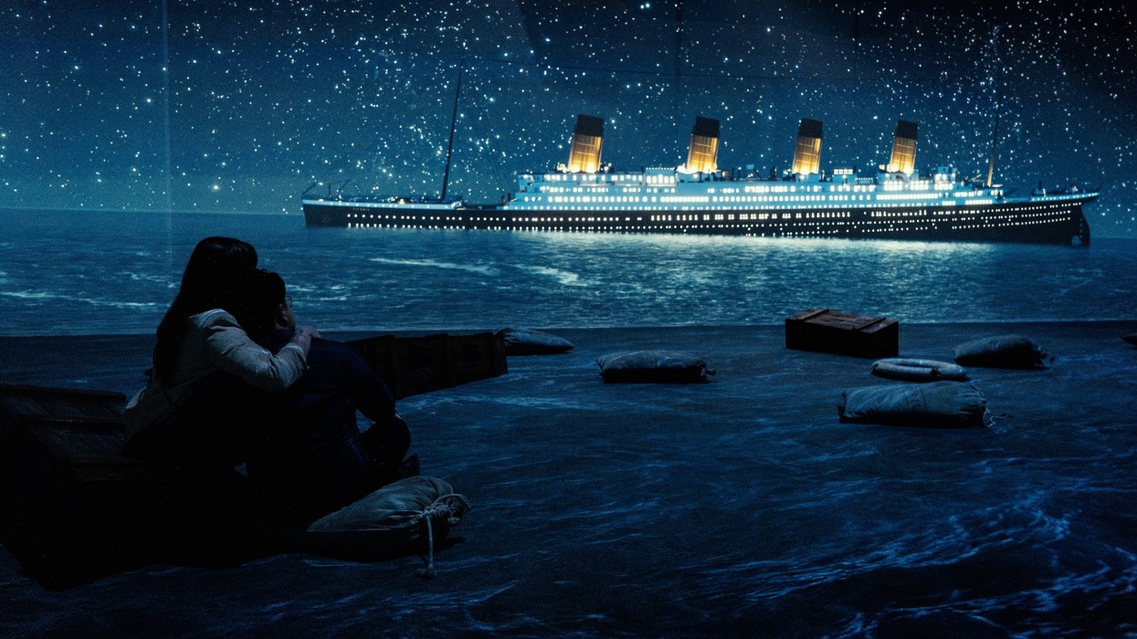 Couple sits floor surrounded by projections in Titanic: An Immersive Voyage